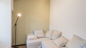 A modern living room with a light-colored sectional sofa, a floor lamp, and a fluffy white rug.