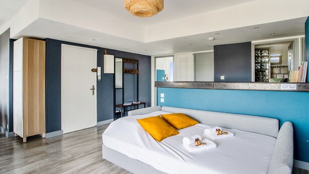 Une chambre à coucher moderne avec un grand lit, une table de chevet, un miroir et un luminaire suspendu.