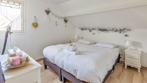 Een keurig opgemaakt slaapkamer met een bed, nachtkastjes, een lamp en decoratieve wanddecoraties.