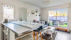 Een moderne keuken met een centraal eiland, barstoelen en een eettafel.