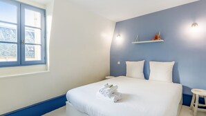 A bedroom with a large bed, a window, and a blue accent wall.