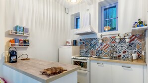 A modern kitchen with white cabinetry, a built-in stove, and a colorful backsplash.