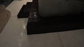 Un jacuzzi con luz azul, rodeado por una terraza de madera y un pequeño banco negro.