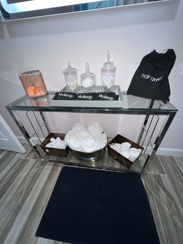Una mesa de vidrio con productos de maquillaje y toallas.