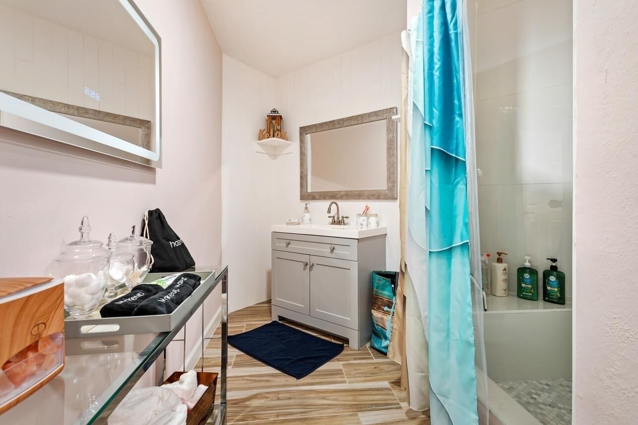 A compact bathroom with a vanity, a mirror, and a shower area.