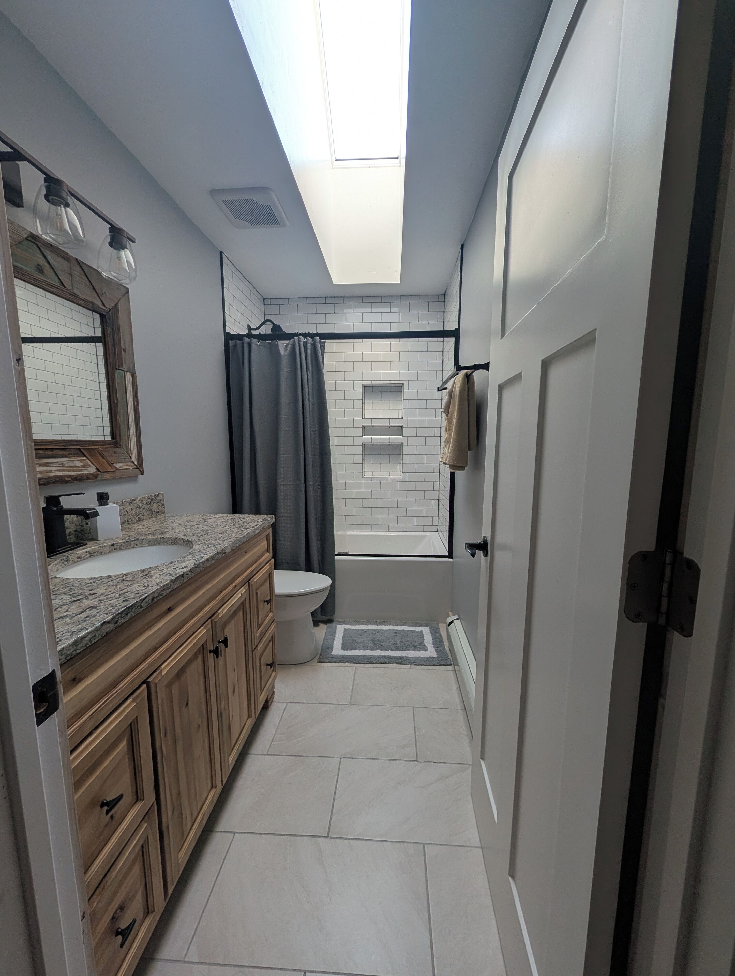 Un baño moderno con tragaluz, una bañera, un inodoro y armarios de madera.