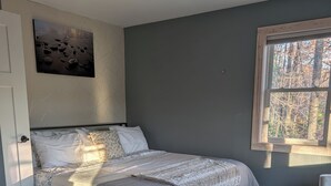 Een slaapkamer met een bed, een raam, een plafondventilator en een vloerkleed.