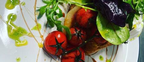 A plate of food with tomatoes, greens, and a drizzle of sauce.