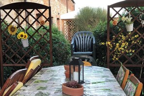 An outdoor patio with a table set for two, surrounded by a wooden fence with decorative elements.