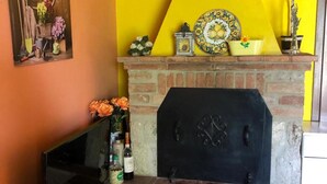 A fireplace with a brick mantel, a yellow wall, and various decorative items including a plate, a vase, and a candle holder.