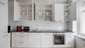Une cuisine moderne avec des meubles blancs, un four Bosch et un évier en acier inoxydable.