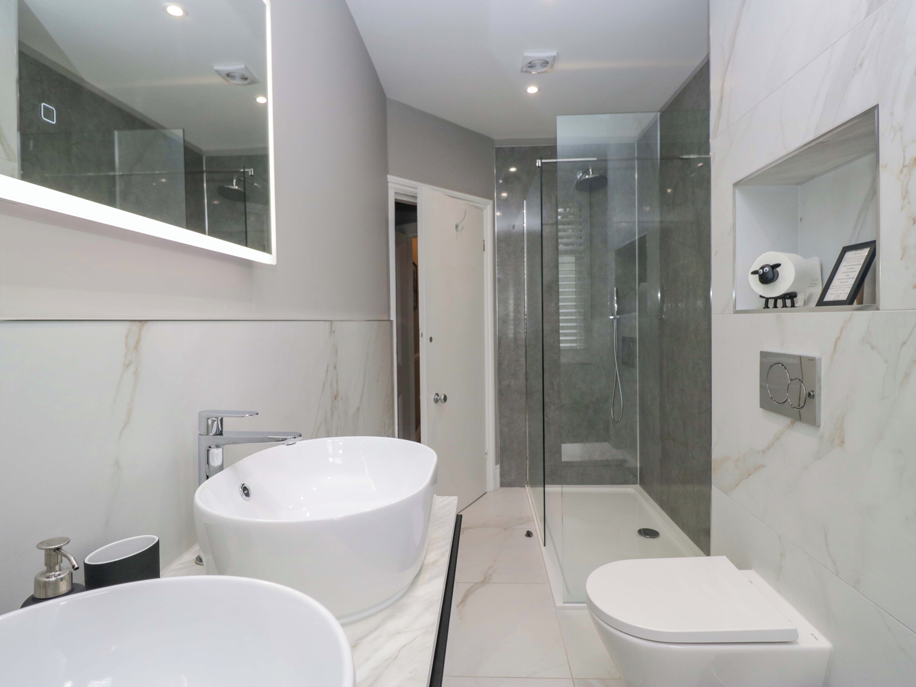 A modern bathroom with a large bathtub, a separate toilet, and a glass-enclosed shower area.