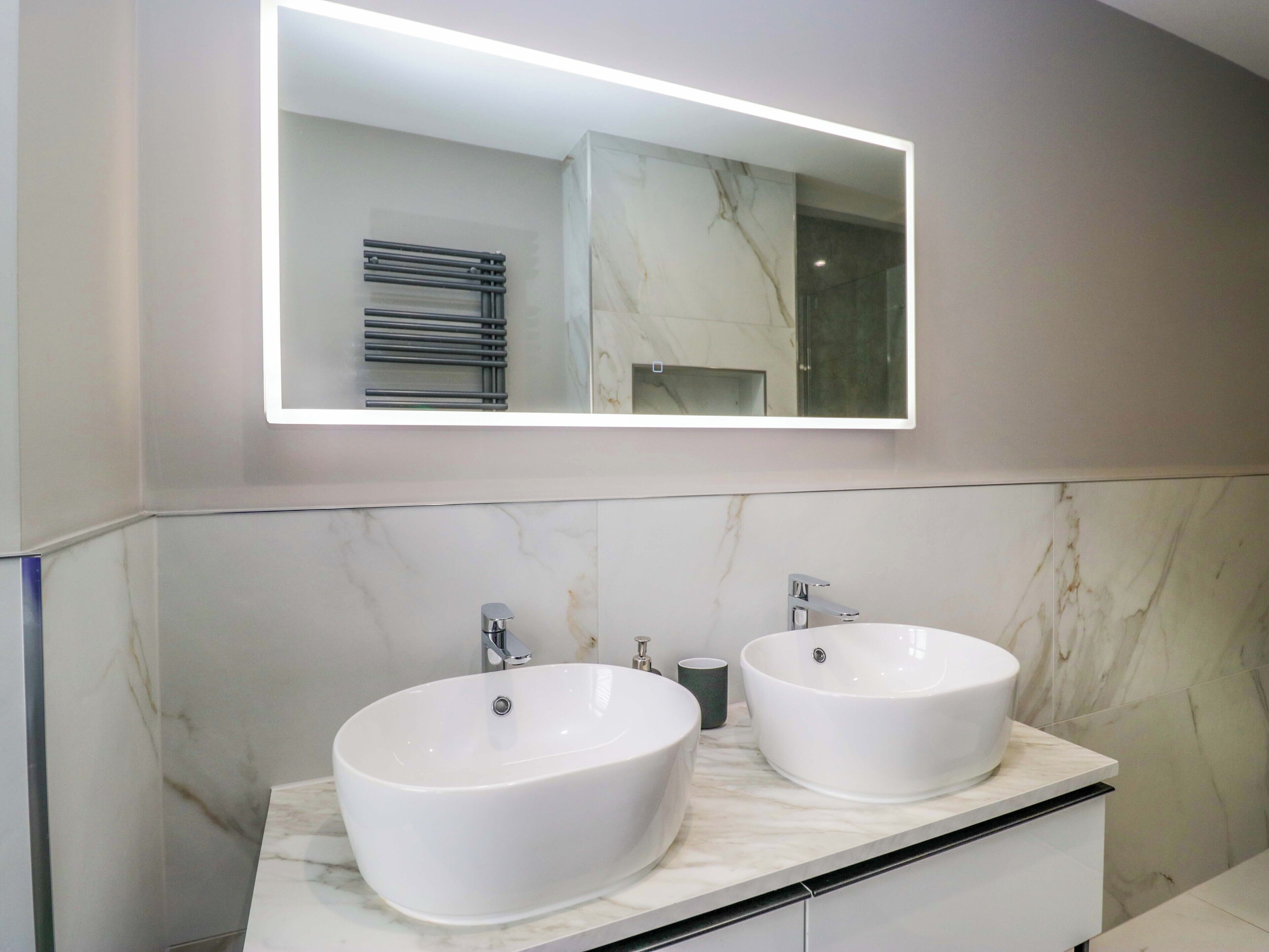 Un bagno moderno con due lavabi bianchi, un grande specchio e un porta asciugamani.