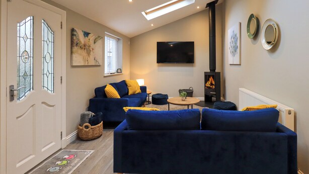 A living room with a sofa, a TV, a fireplace, and a skylight. - Beckmead (Windermere)