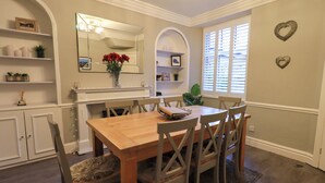A dining room with a wooden table and chairs, a large mirror, and decorative items on shelves. - Beckmead (Windermere)
