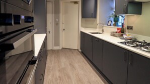 A modern kitchen with dark cabinets, a white countertop, a built-in oven, and a gas stove. - Beckmead (Windermere)
