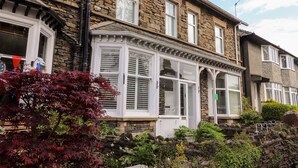 A traditional stone house with a bay window, a stone facade, and a small garden with red-leaved plants. - Beckmead (Windermere)