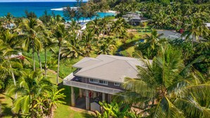 A coastal property with a large house, surrounded by palm trees and a view of the ocean. - STEPS FROM STUNNING MOLOAA BAY (Anahola)
