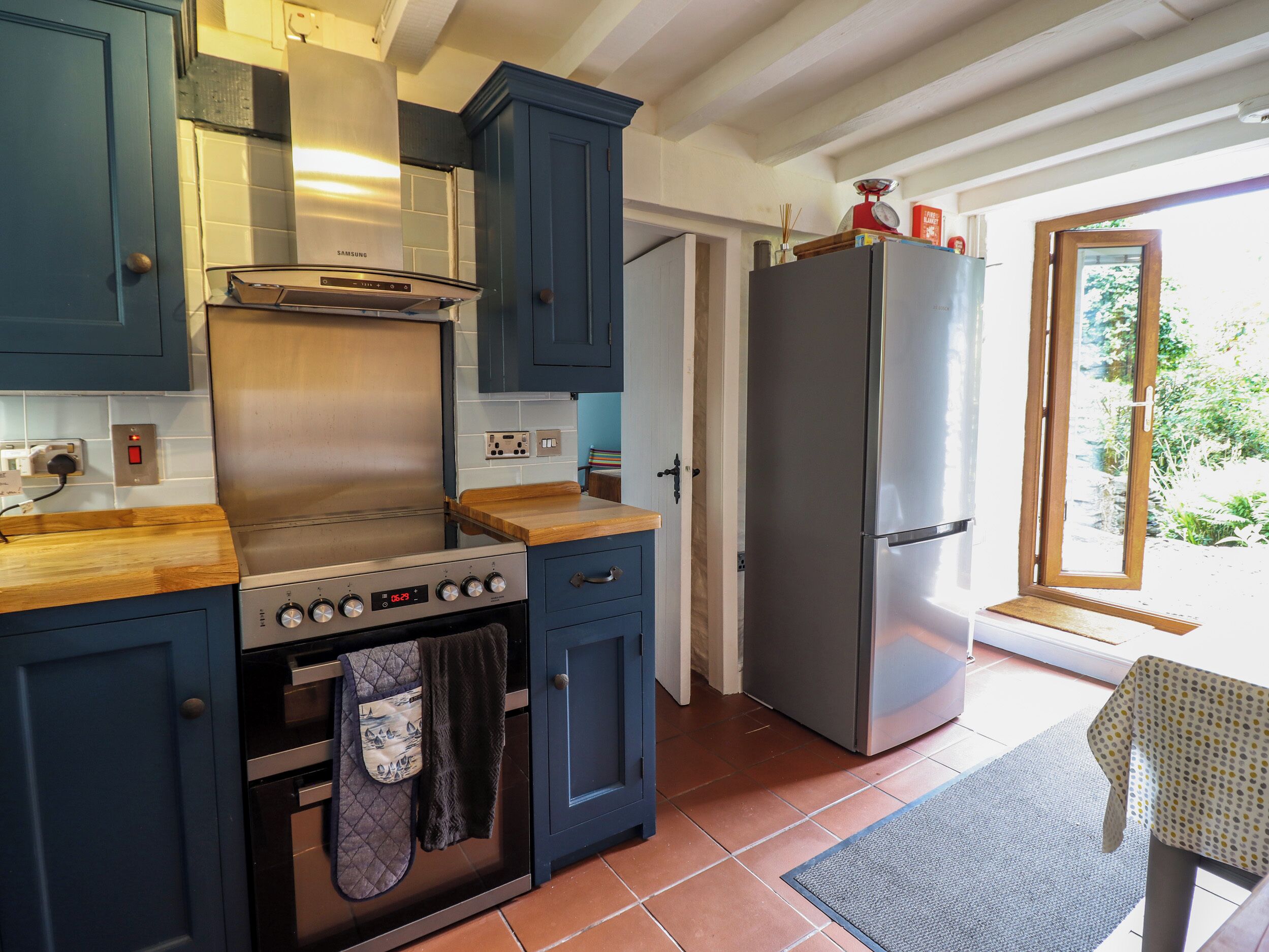 A kitchen with a stainless steel stove, a refrigerator, and blue cabinets.