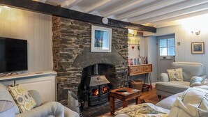 Una sala de estar acogedora con chimenea de piedra, asientos cómodos y una estantería.