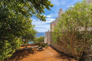 A pathway leading to a stone wall with a view of the sea.