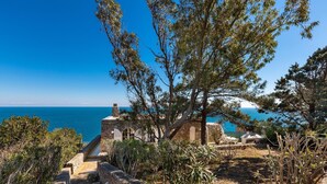 Ein gepflasterter Weg führt zu einem rustikalen Gebäude mit Blick auf das Meer.