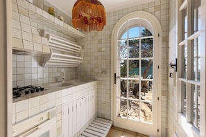 A kitchen with white tiles, a stove, and a large arched window. - 2750 Villa Petra by Barbarhouse (Gagliano del Capo)