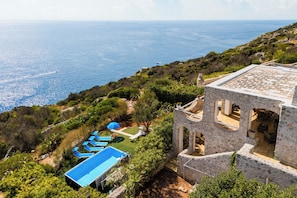 A coastal property with a swimming pool, lounge chairs, and a stone building with arches. - 2750 Villa Petra by Barbarhouse (Gagliano del Capo)