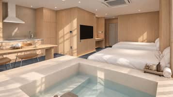Una habitación de hotel moderna con una cama grande, un pequeño rincón de cocina, una zona de estar y un jacuzzi.