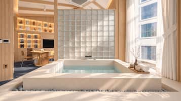 A modern spa room with a large bathtub, a wooden reception desk, and a wall of framed pictures.