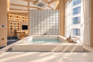 Un spa moderno con una bañera grande, un mostrador de recepción de madera y una pared decorada con cuadros.
