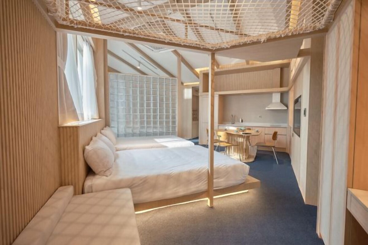 A modern hotel room with a large bed, a desk, and a seating area.