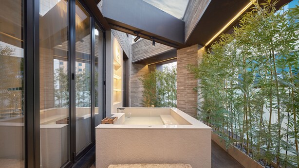 Un baño moderno con una bañera independiente, ventanas amplias y vistas a zonas verdes.