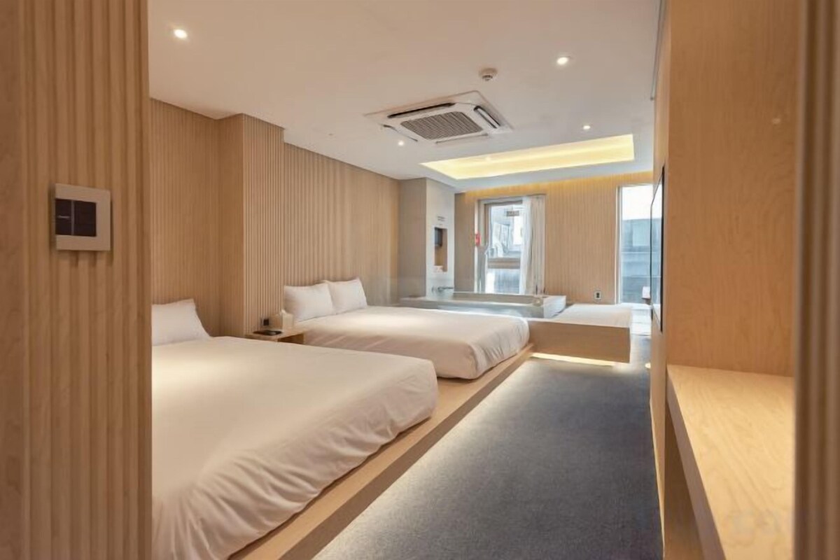 Een hotelkamer met twee bedden, een tafeltje en uitzicht op de stad.