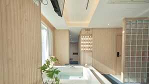 Un baño moderno con una bañera grande, paneles de madera y una lámpara fijada a la pared.