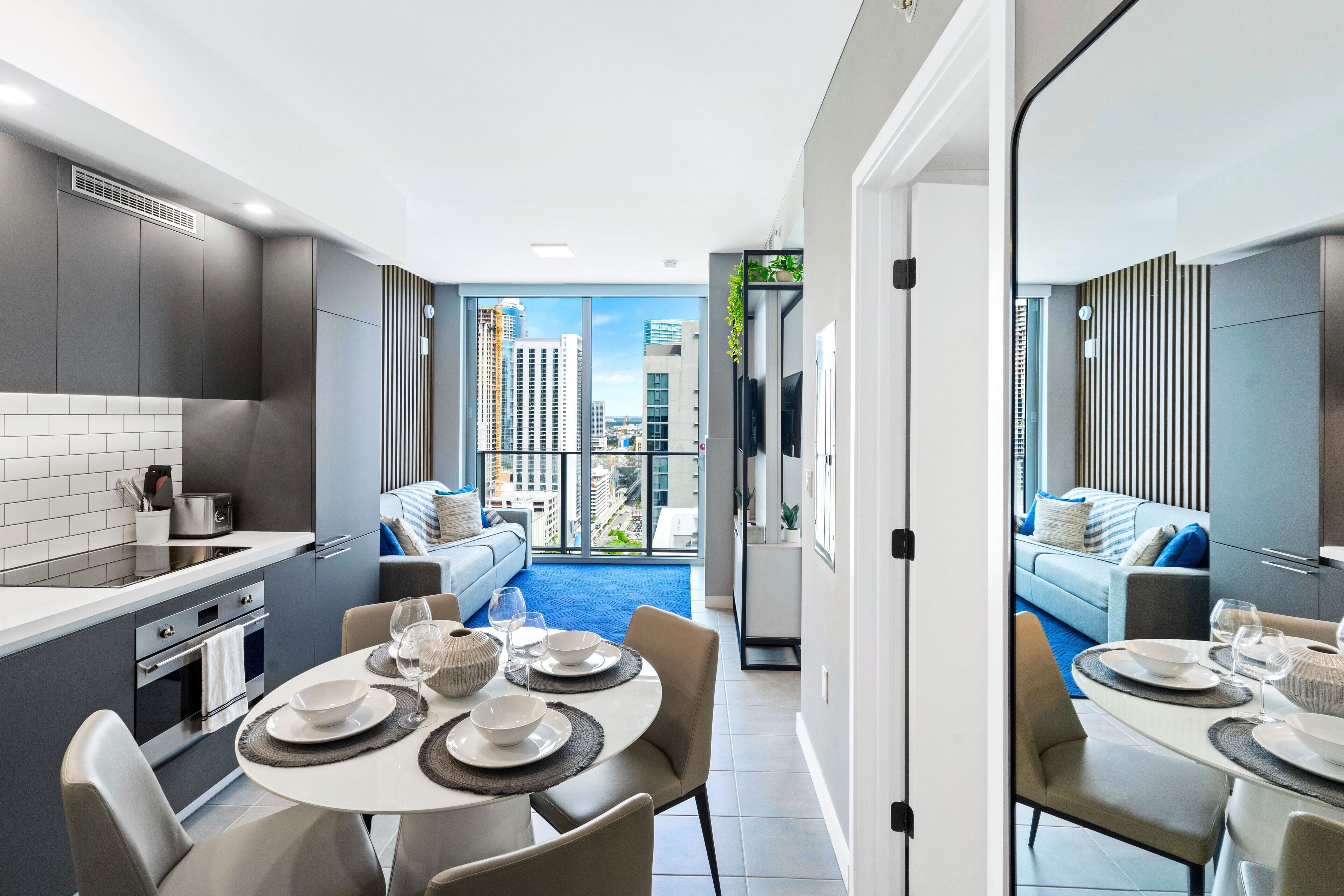 A modern kitchen with a dining area, large windows, and a view of the city.
