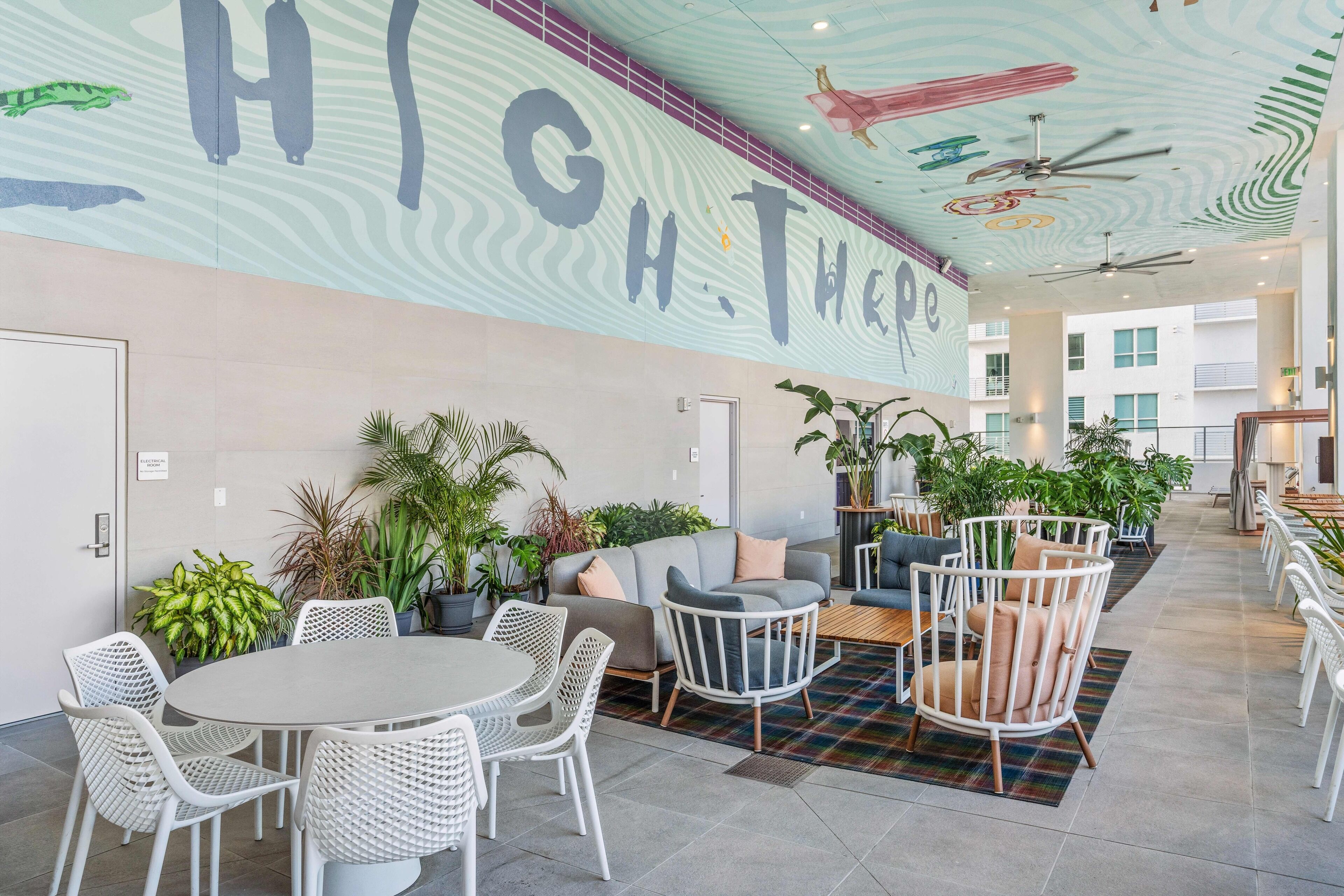 A spacious indoor area with a high ceiling, a large mural, and seating arrangements.