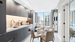 A modern kitchen with grey cabinets, a white countertop, and a dining area with a round table and chairs. - Modern High-Rise Condo with Pool/Gym, in Central DT MIAMI! (Miami)