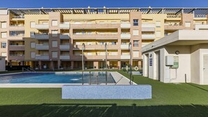 Un edificio residenziale a più piani con piscina, balconi e un'area esterna coperta.