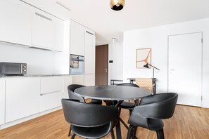 A modern kitchen with white cabinets, a microwave, and a round dining table with four chairs.