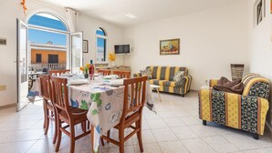 A dining area with a table set for four, a sofa, and a television on the wall.