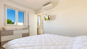 A bedroom with a large bed, a dresser, a TV, and a window with a view of the sky and trees. - 2508 Villetta Blanca by Barbarhouse (Castrignano del Capo)
