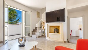 A modern living room with a fireplace, a flat-screen TV, and a staircase leading to an upper floor. - 2508 Villetta Blanca by Barbarhouse (Castrignano del Capo)