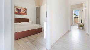 A bedroom with a bed, a painting, and a hallway leading to an outdoor area. - 3045 Appartamento Belloluogo by Barbarhouse (Lecce)
