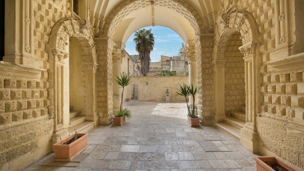 An arched corridor with stone walls and potted plants. - 3045 Appartamento Belloluogo by Barbarhouse (Lecce)