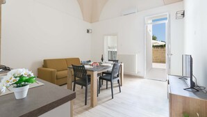 A modern living space with a dining area, a sofa, and a TV. - 3045 Appartamento Belloluogo by Barbarhouse (Lecce)