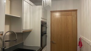 Een kleine keuken met een spoelbak, roestvrijstalen apparatuur en een houten deur.