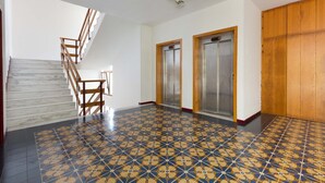 A spacious hallway with a patterned floor, a wooden staircase, and two elevators. - 2847 Appartamento Biancaluna by Barbarhouse (Vernole)