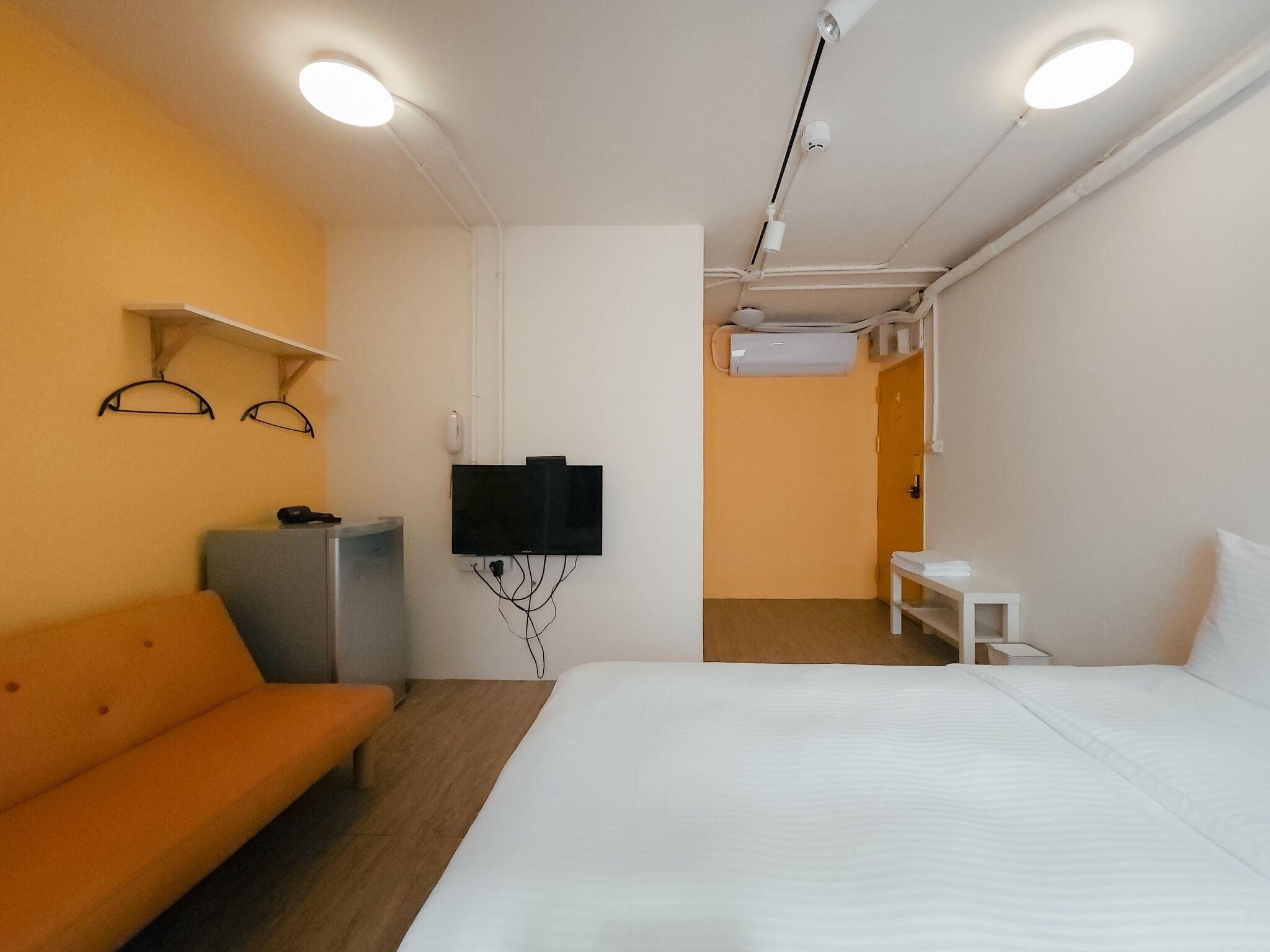 Ett hotellrum med en säng, en soffa, en TV och en luftkonditioneringsanläggning.