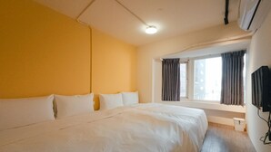 A hotel room with a large bed, a window with curtains, and a mounted television. - Taipei Inn (Taipei)